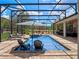 Stunning screened-in pool area with a tanning ledge, patio seating, lush greenery, and idyllic backyard views at 20199 Sweetwood Ln, Clermont, FL 34715