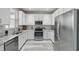 Updated kitchen with white cabinets, stainless steel appliances, granite counters, and wood-look flooring at 231 Chestnut Creek Dr, Apopka, FL 32703