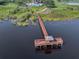 An aerial view of a long wooden dock leading out to a covered seating area over a very dark lake at 2520 Oakington St, Winter Garden, FL 34787