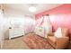 Pink Bedroom with a crib featuring a crown canopy, charming accents and a comfortable chair at 2752 Grand Central Ave, Tavares, FL 32778