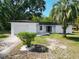 Beautiful exterior view of a white home showcasing a well-kept lawn, landscaping, and attached garage at 43 Lake Court Loop, Ocala, FL 34472