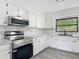 Well-lit kitchen features stainless steel appliances, white cabinets, and marble backsplash at 43 Lake Court Loop, Ocala, FL 34472