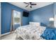 Comfortable bedroom with a large window, blue walls, modern decor, ceiling fan, and warm lighting at 4313 Gumbo Limbo Dr, Orlando, FL 32822