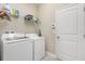 Functional laundry room includes washer, dryer, shelving for storage, and access door for added convenience at 5353 Oakbourne Ave, Davenport, FL 33837