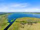 Expansive aerial shot of a large, deep blue lake surrounded by lush green landscapes and marshy wetlands under a clear sky at 5370 Whispering Pine Cir, St Cloud, FL 34771