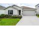 Well-maintained single-story home with a two-car garage, green lawn, and a well-landscaped front yard at 818 Kapi Dr, Groveland, FL 34736