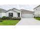 Single-story home featuring a two-car garage, neat landscaping, and a green lawn under a cloudy sky at 818 Kapi Dr, Groveland, FL 34736