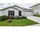 Single-story home showcasing a two-car garage, dark shutters, landscaping, and a neatly manicured green lawn at 818 Kapi Dr, Groveland, FL 34736