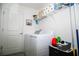 Functional laundry room with a washer, dryer, overhead shelving, and gray tile floors at 818 Kapi Dr, Groveland, FL 34736