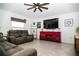 Comfortable living room with a ceiling fan, gray sofa, red console, and large television at 818 Kapi Dr, Groveland, FL 34736