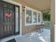 Close up of cozy front porch with chairs, and black door, and lots of natural light at 9189 Camden Gardens St, Orlando, FL 32827