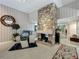 Cozy living room with stone fireplace, comfortable blue armchairs, and stairway in the background at 103 Red Cedar Dr, Longwood, FL 32779