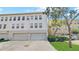 View of the back of the three story townhouse with two garage doors and a vehicle parked in the driveway at 1038 Waterside Dr, Celebration, FL 34747