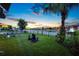 Serene backyard at sunset with lake view, fountain, mature trees, and comfortable seating, ideal for evening relaxation at 10529 Royal Cypress Way, Orlando, FL 32836