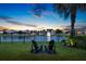 Backyard at sunset with lake views, fountain, comfortable seating, and lush greenery creating a tranquil outdoor space at 10529 Royal Cypress Way, Orlando, FL 32836