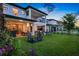 Beautiful backyard at dusk with patio, outdoor kitchen, covered seating, pool, and lake views, creating a perfect retreat at 10529 Royal Cypress Way, Orlando, FL 32836