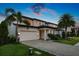 Elegant two-story home at twilight with a three-car garage, brick driveway, and manicured landscaping at 10529 Royal Cypress Way, Orlando, FL 32836