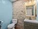 Modern bathroom with a light blue accent wall, brown tile walls, and neutral tiling at 1112 Winding Water Way, Clermont, FL 34714