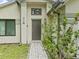 Inviting front entrance featuring a sleek, dark door, decorative plants, and manicured landscaping at 1112 Winding Water Way, Clermont, FL 34714