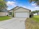 Charming single-story home displaying a clean two-car garage and well-kept lawn with a vibrant splash of nature at 1112 Winding Water Way, Clermont, FL 34714