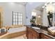 Well-lit bathroom features a soaking tub, vanity, granite counters and tile flooring at 14724 Avenue Of The Rushes, Winter Garden, FL 34787