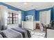 Spacious bedroom featuring blue walls, white trim, a large window, and stylish furniture at 14724 Avenue Of The Rushes, Winter Garden, FL 34787