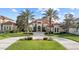 Well-manicured front yard featuring a circular driveway, lush green grass, and mature palm trees at 14724 Avenue Of The Rushes, Winter Garden, FL 34787