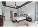 Airy primary bedroom boasts tray ceilings, an adjacent seating area, and neutral colors at 14724 Avenue Of The Rushes, Winter Garden, FL 34787