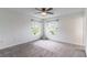 Spacious bedroom with plush carpet, two windows, and a modern ceiling fan at 15030 Book Club Rd, Winter Garden, FL 34787