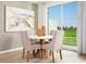Cozy dining area with backyard view, featuring a white round table with modern upholstered chairs at 16382 Bird Of Paradise Ave, Clermont, FL 34714