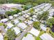 An aerial view showcases a mobile home in a lush community with mature trees near a tranquil pond and shopping center at 200 Palm Meadows Dr, Eustis, FL 32726