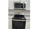 The kitchen features a stainless steel microwave and electric range with a black cooktop and granite countertops at 205 Brighton Way, Casselberry, FL 32707
