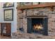 Close-up of a brick fireplace with a wooden mantel, decorative art, and fireplace tools at 2106 Tuscarora Trl, Maitland, FL 32751