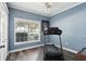 Home gym with treadmill, blue walls, and large window overlooking neighborhood at 2215 Guiana Plum Dr, Orlando, FL 32828