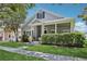 Charming home featuring a cozy front porch, lush green lawn, and mature trees providing shade at 2215 Guiana Plum Dr, Orlando, FL 32828