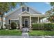Charming gray home with a covered front porch, manicured lawn and garden and beautiful blue sky at 2215 Guiana Plum Dr, Orlando, FL 32828