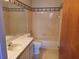 Cozy bathroom with tiled tub-shower, standard toilet, and sink with floral accents at 2320 Pebble Brook Rd, Kissimmee, FL 34741
