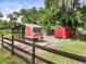 A custom-built chicken coop and shed sit behind a black, split rail fence at 2326 Florida Ave, Oviedo, FL 32765