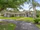Inviting home exterior with manicured lawn, circular driveway, brick walkway, arched entry, and mature trees at 2326 Florida Ave, Oviedo, FL 32765