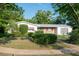 An eye-level front exterior showing a white house, manicured shrubs, brick details and mature trees at 2361 Kimberly Dr, Deltona, FL 32738