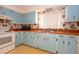 Retro kitchen with blue cabinets, double sink, orange countertops, and classic wallpaper, creating a unique aesthetic at 2361 Kimberly Dr, Deltona, FL 32738