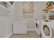 Functional laundry area with washer, dryer, storage, and stylish wall decor at 2449 Southlawn Ln, Clermont, FL 34714