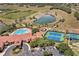Aerial view of community amenities including a pool, clubhouse, tennis courts, and a scenic pond at 3677 Serena Ln, Clermont, FL 34711