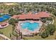 Aerial view of a community pool and clubhouse with tennis courts, surrounded by lush landscaping at 3677 Serena Ln, Clermont, FL 34711
