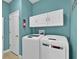 Laundry room with washer, dryer, and storage cabinets with an turquoise accent wall at 3677 Serena Ln, Clermont, FL 34711