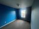 A bedroom with bright blue walls, a window, and neutral carpet at 4650 Staghorn Dr # 500, Orlando, FL 32808