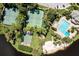 Aerial view of tennis courts, beach volleyball court, and an oversized pool, surrounded by lush landscaping at 5154 Majestic Woods Pl, Sanford, FL 32771