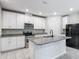 Modern kitchen featuring white cabinets, granite countertops, stainless steel appliances, and a functional center island at 596 Sun Warbler Way, St Cloud, FL 34771