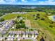 Location pin over aerial neighborhood view of houses near a lake and farmland at 5967 Churchill Square Way, Groveland, FL 34736