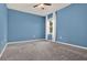 Bedroom with blue walls features neutral carpet, ceiling fan, and sheer curtains at 5967 Churchill Square Way, Groveland, FL 34736